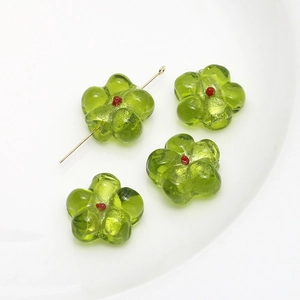 Macro view of green and red flower-shaped glass beads for DIY jewelry making