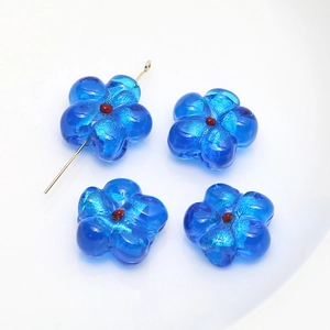 Close-up of blue glass flower beads with a gold metal T-pin for DIY jewelry making