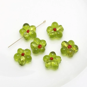 Macro shot of green glass flower beads with red centers for DIY jewelry making