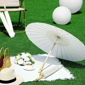 White wedding paper umbrella set on green grass for outdoor party and ceremony decor