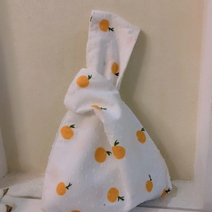 Japanese knot wrist bag with orange pattern and 3D polka dots on white cotton fabric