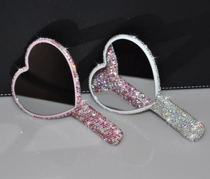 Close-up of heart-shaped handheld mirrors with sparkling pink and silver rhinestones