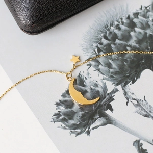 Detailed macro view of 18K gold plated moon and star pendant on a delicate chain