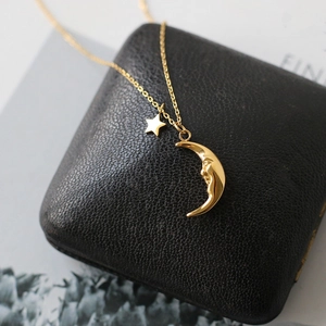 Detailed close-up of crescent moon and star pendant on a black leather jewelry box