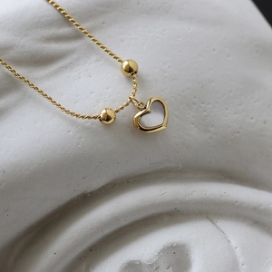 Macro shot of 18K gold plated heart necklace with white shell inlay and double beads