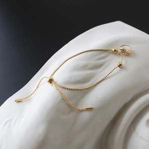 Close-up of golden adjustable chain bracelet with shell heart pendant on a stone