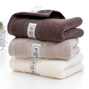 Set of three stacked premium cotton face towels in brown, khaki, and cream white