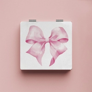 Detail of portable square mirror featuring a pink watercolor bow on a minimalist background