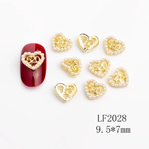 Close-up of heart-shaped 520 nail art charms with golden metal and white pearls