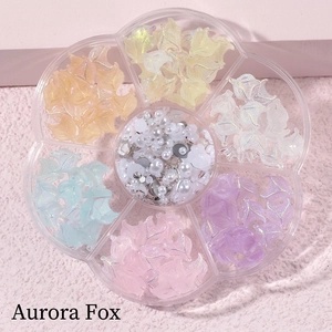 Macro detail of aurora fox nail charms with pearls and rhinestones in a petal box