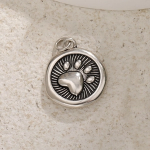 Silver round pendant featuring a raised cat paw design with fine radial textures