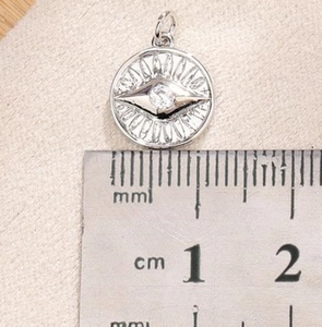 Detail showing the 12mm silver sun pendant with zircon on a measuring scale ruler