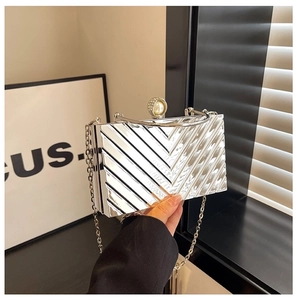 Detailed close-up of silver acrylic evening clutch with V-shaped texture and pearl clasp