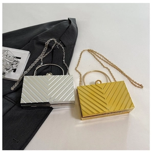 Detail of silver and gold acrylic evening bags with V-shaped wave texture and pearl clasp