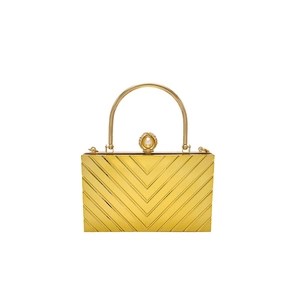 Detail of golden chevron evening clutch featuring a metal top handle and pearl clasp