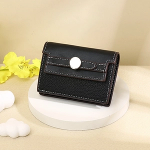 Close-up of black lychee grain leather card holder with white stitching and metal buckle