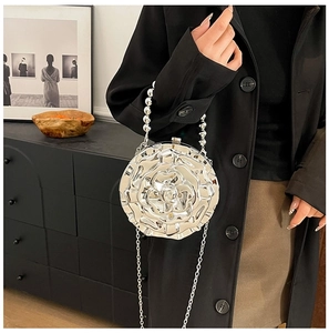 Detail of silver rose metallic handbag with beaded handle and chain strap on person