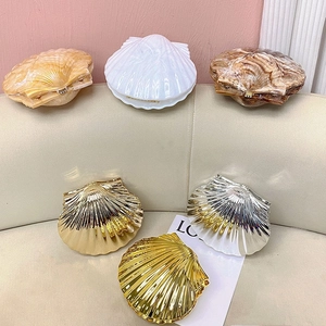 Detail view of shell-shaped evening bags in marble, pearl white, and metallic finishes