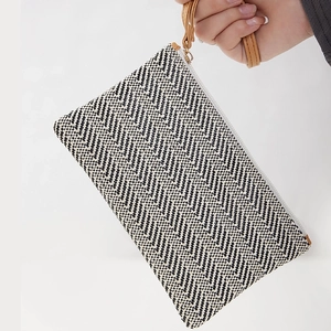 Chic straw woven clutch bag with black and white herringbone pattern and brown leather strap