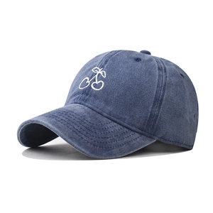 Close-up of cherry embroidery detail on washed blue denim cotton baseball cap
