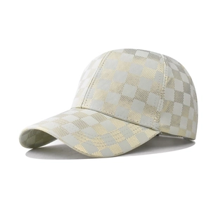 Macro detail of white baseball cap with gold checkered pattern and textured satin finish