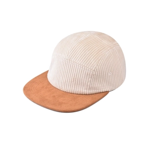 Detail of five-panel corduroy cap featuring beige texture and brown suede short brim