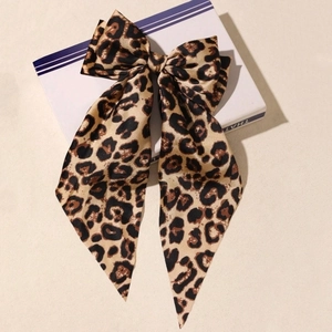 Elegant satin bow hair clip with leopard print design on a decorative display box