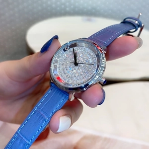 Close-up of sparkling crystal-encrusted dial with blue leather strap on a women's watch