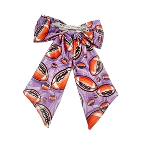 Detail of purple rugby bow hair clip showing fabric texture and metal fastener