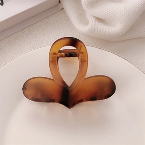 Detailed view of amber tortoiseshell hair claw clip on a white plate with soft lighting