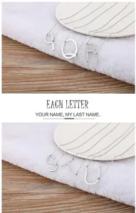 Close-up of minimalist uppercase silver titanium steel letter necklaces on a soft background