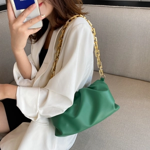 Detail of green pleated cloud bag with chunky gold chain strap worn on the shoulder