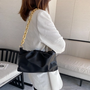 Close-up of black PU leather cloud bag with chunky gold chain strap worn by a model