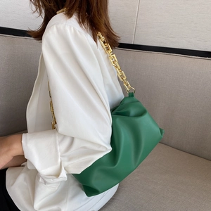 Green leather cloud bag with gold chain strap shown on model for crossbody styling