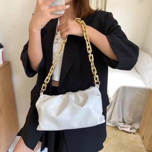Close-up of white ruched cloud bag featuring a chunky gold chain strap held by a model