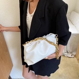 Detail of white cloud bag with chunky gold chain strap worn with black blazer