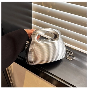 Detail of silver wavy metallic evening bag with chain strap held by a model