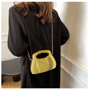 Detailed back view of a gold metallic hollow birdcage crossbody bag on a black blazer