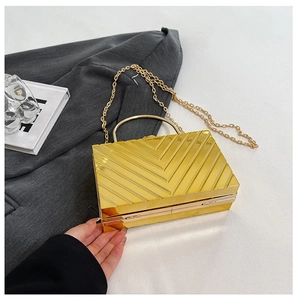 Detailed close-up of a gold evening clutch featuring a stylish chevron texture and metal handle