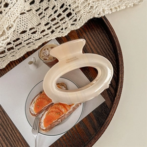 Macro detail of large beige acrylic hair claw clip with France Handmade text on wood