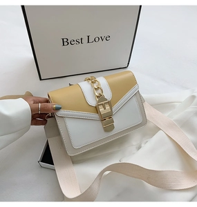 Detail of yellow and white contrast crossbody bag with gold chain and wide shoulder strap