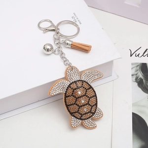 Detail of sea turtle keychain with brown rhinestones, suede tassel and silver bell charms