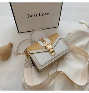 Detail view of the yellow and white crossbody bag with gold metal buckle and wide strap