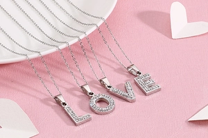 Vue détaillée de pendentifs LOVE argentés avec strass sur une chaîne à maillons