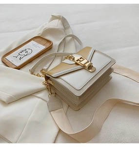 Detail showing the white and beige patchwork shoulder bag with gold hardware and strap