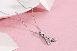 Gros plan d'un pendentif lettre A en argent avec zircons étincelants sur fond rose