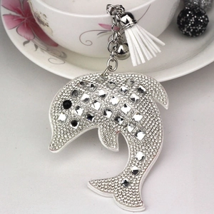 Detail view of a silver dolphin keychain with sparkling rhinestones and white tassel