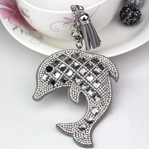 Detail of dolphin bag charm featuring sparkling crystals, silver bell and grey tassels