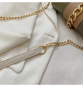 Detail of premium gold metal chain and off-white leather strap on a stylish crossbody bag