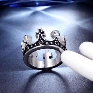 Close-up of a silver crown ring with black cross details on a dark textured background